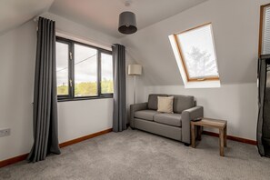 Ein modernes Wohnzimmer mit einer Couch, einem kleinen Tisch, einer Lampe und einem Oberlicht.