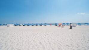 Una playa con arena blanca, sombrillas azules y sillas de playa.