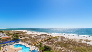 Un resort en la playa con piscina, sombrillas y vistas claras al océano.