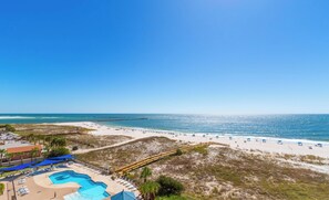 Un resort en la playa con piscina, sombrillas y vistas claras al océano.