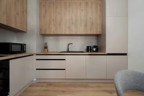 Una cucina moderna con mobili in legno, un forno a microonde nero, un lavello e un bollitore.