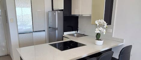 A modern kitchen with a central island, black bar stools, and stainless steel appliances.