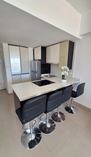 A modern kitchen with a central island, black bar stools, and stainless steel appliances. - Ideal apartment for your vacations in Margarita Island (Nueva Esparta)