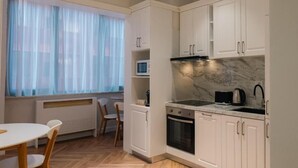 A compact kitchen with white cabinets, a microwave, a stove, and a dining area with a table and chairs.
