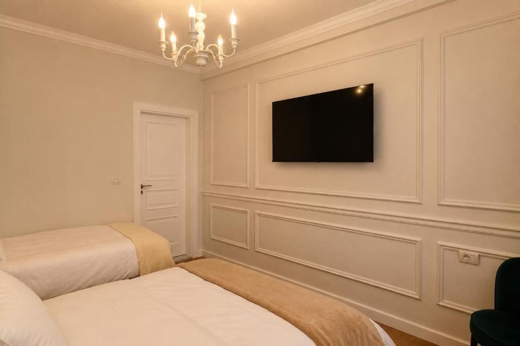Habitació d'hotel amb dos llits, televisió de pantalla plana penjada a la paret, un penjador i una porta.