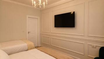 Habitació d'hotel amb dos llits, televisió de pantalla plana penjada a la paret, un penjador i una porta.