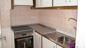 A kitchen with white cabinets, a granite countertop, a stainless steel sink, and an oven. - Family apartment, sea view, parking - 7 guests (Gandia)