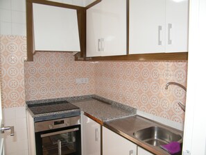 Eine Küche mit weißen Schränken, einer Granitarbeitsplatte, einer Spüle aus Edelstahl und einem Backofen.