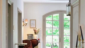 Une pièce dotée d’une grande fenêtre en arc de cercle, d’une cheminée et de deux fauteuils rembourrés.