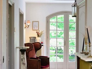 A room with a large arched window, a fireplace, and two upholstered chairs. - Spacious and peaceful villa - 15 guests (HERBEVILLE)
