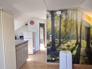 Una cocina con refrigerador, microondas y un reloj en la pared.