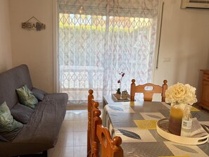 Ein Wohnzimmer mit einer Couch, Holzstühlen, einem Tisch mit einer Vase und einem gemusterten Teppich.