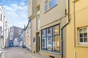 A narrow street with buildings on both sides, a clear sky, and a sign indicating a business establishment. - Harbour Retreat for Two in Tenby - Dog Welcome (Pembrokeshire)