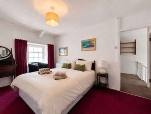 Una camera d'albergo con un letto, una scrivania, una sedia, una lampada, un quadro e una scala.