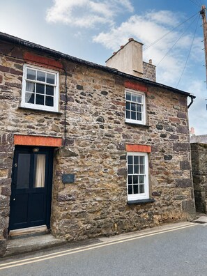 A stone building with a black door, two windows with white frames, and a sign indicating the name 'Cecily.' - Heart of St Davids Cottage| Parking | Pet Friendly (St Davids)