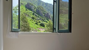 A room with a bed, a window with a view of a green landscape. - Modern studio near slopes - 4 guests (Aisa-Candanchú)