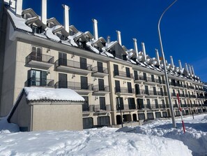 A multi-story hotel with balconies, snow-covered roofs, and a clear blue sky. - Modern studio near slopes - 4 guests (Aisa-Candanchú)