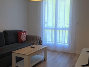 A living room with a sofa, a coffee table, and a large window with a view. - Renovated mountain studio - 4 guests (Aisa-Candanchú)