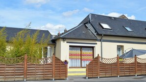 A residential building with a sloped roof, a gated entrance, and a visible garage door. - Spacious lodging in village center - 7 guests (ALAINCOURT)
