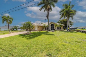 A house with a lawn, palm trees, and a clear sky. - Great Location! Close to library, 3 bed - 2bath and pool (Cape Coral)