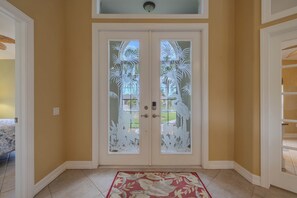 A double door with frosted glass panels, a red and white patterned rug, and a ceiling fan. - Great Location! Close to library, 3 bed - 2bath and pool (Cape Coral)