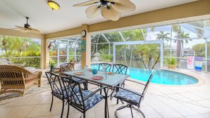 A poolside area with a table and chairs, a ceiling fan, and a view of the pool. - Great Location! Close to library, 3 bed - 2bath and pool (Cape Coral)