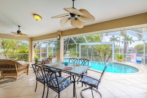 A poolside area with a table and chairs, a ceiling fan, and a view of the pool. - Great Location! Close to library, 3 bed - 2bath and pool (Cape Coral)
