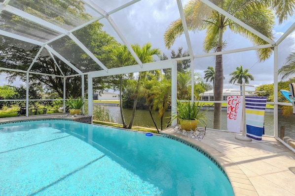 A covered swimming pool with a view of palm trees and a body of water. - Great Location! Close to library, 3 bed - 2bath and pool (Cape Coral)