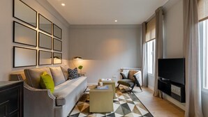 Ein modernes Wohnzimmer mit Sofa, Sessel, Couchtisch und Fernseher.