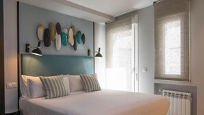 Ein Schlafzimmer mit einem Bett, Nachttischlampen, einem Wandbild und einem Fenster mit Jalousien.