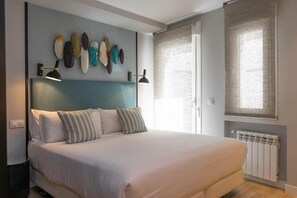 Un dormitorio con cama, lámparas de noche, un cuadro en la pared y una ventana con persianas.