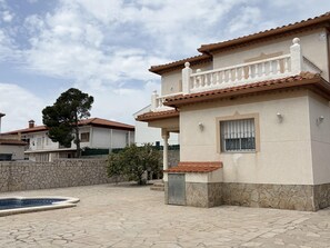 Um edifício residencial com fachada de pedra, telhado ladrilhado e piscina.