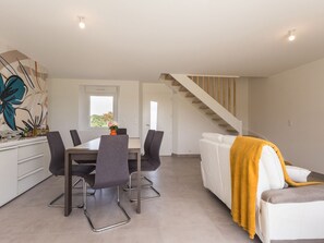 Une cuisine moderne avec une table à manger, des chaises et un escalier menant à un niveau supérieur.