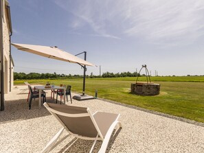 Une terrasse extérieure avec une table, des chaises, un parasol et une sculpture métallique décorative.