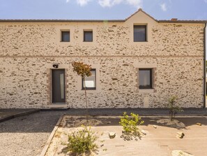 Un bâtiment doté d’une façade en pierre, de trois fenêtres et d’une porte.