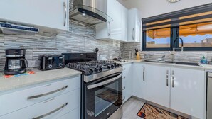 Una cucina moderna con piano cottura a gas, forno, macchina del caffè e tostapane.