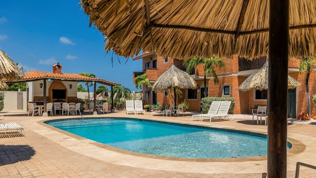 Una piscina con lettini da sole e una zona relax ombreggiata.