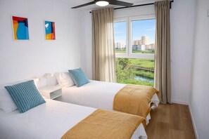 A hotel room with two beds, a window with curtains, and artwork on the wall. - Apartamento La Mar Inmomart (Peñiscola)