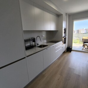 A modern kitchen with a sink, a stove, and cabinets. - Apartamento La Mar Inmomart (Peñiscola)