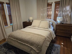 A bedroom with a bed, two bedside tables, a lamp, and a window with blinds. - Walk to Brookside, Shops/Dining, 3BR, patio, backyard bar.   9 miles 2 World Cup (Kansas City)