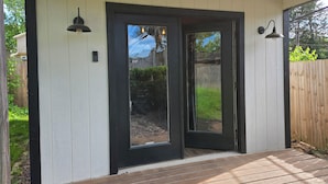 A house with a black-framed door, a wooden deck, and two wall-mounted lights. - Walk to Brookside, Shops/Dining, 3BR, patio, backyard bar.   9 miles 2 World Cup (Kansas City)