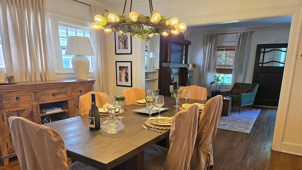 A dining area with a long table, chairs, a chandelier, and a view of a living room. - Walk to Brookside, Shops/Dining, 3BR, patio, backyard bar.   9 miles 2 World Cup (Kansas City)