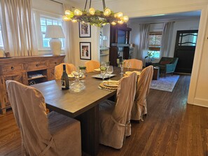 A dining area with a long table, chairs, a chandelier, and a view of a living room. - Walk to Brookside, Shops/Dining, 3BR, patio, backyard bar.   9 miles 2 World Cup (Kansas City)