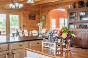 Ein Holzinterieur mit Küchenzeile, einer Blumenvase und einer Bar mit Flaschen und Gläsern.
