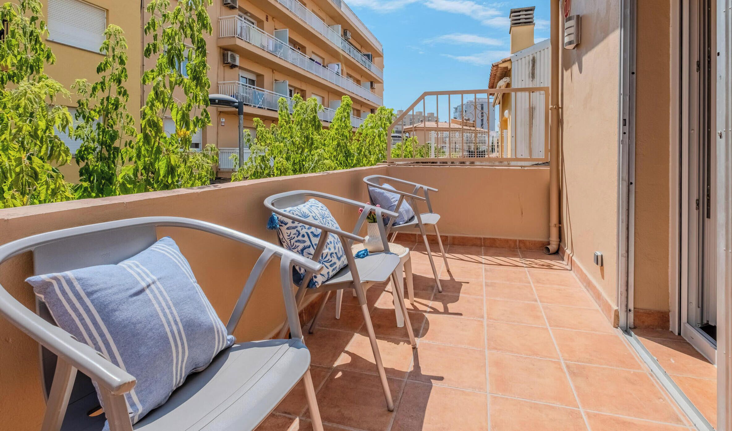 Ein Balkon mit zwei Stühlen und einem Tisch, umgeben von einem Gebäude mit mehreren Balkonen.