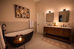 Un baño moderno con una bañera independiente, un tocador con espejo y una obra de arte abstracta en la pared.