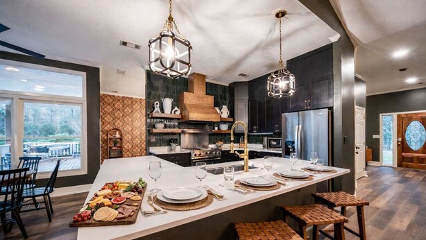 A modern kitchen with a large island, stainless steel appliances, and hanging pendant lights.