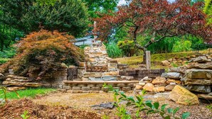 A stone staircase leading up to a structure, surrounded by greenery and trees.