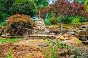 Una escalera de piedra que sube hacia una construcción, rodeada de follaje y árboles.