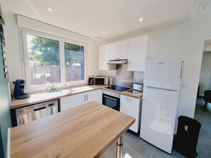A modern kitchen with white cabinets, a wooden countertop, a built-in oven, and a refrigerator.